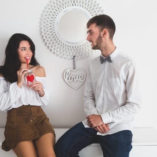 girl-smiling-while-drinking-from-glass-with-red-straw